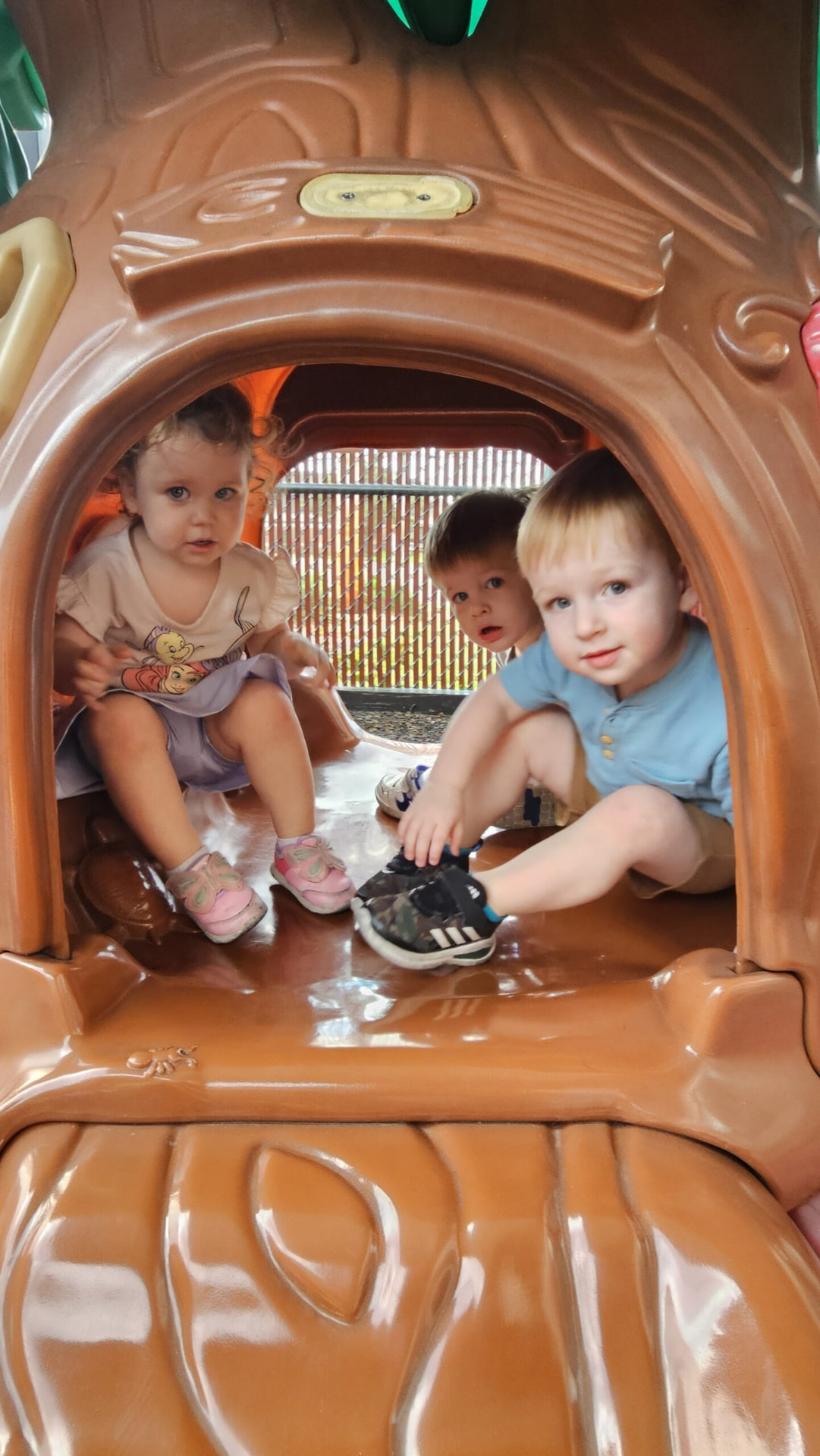 Three toddlers playing inside a playground climber at our Crestwood school.